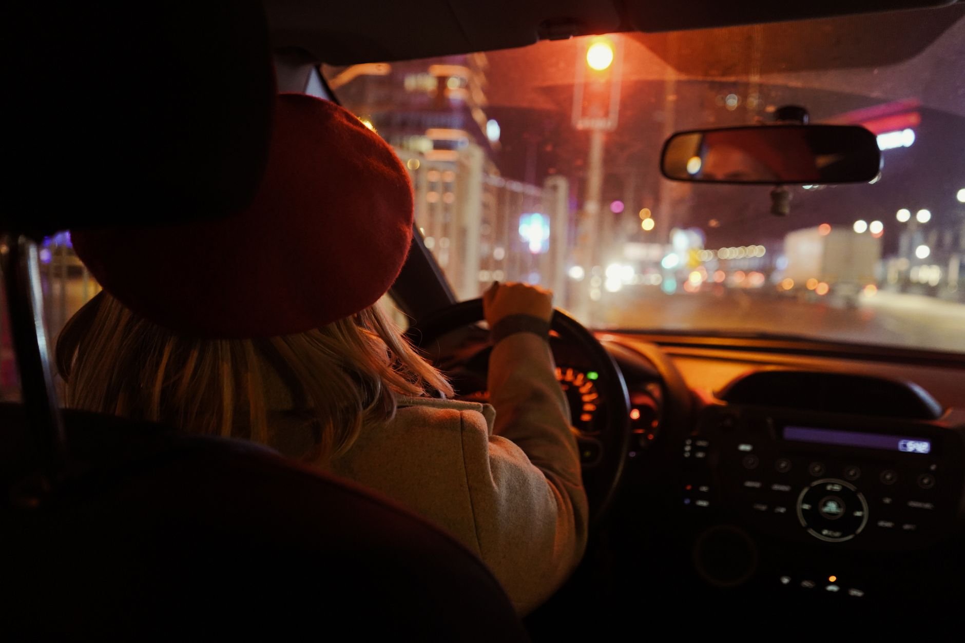 Person driving through a city at night, lights streaming past
