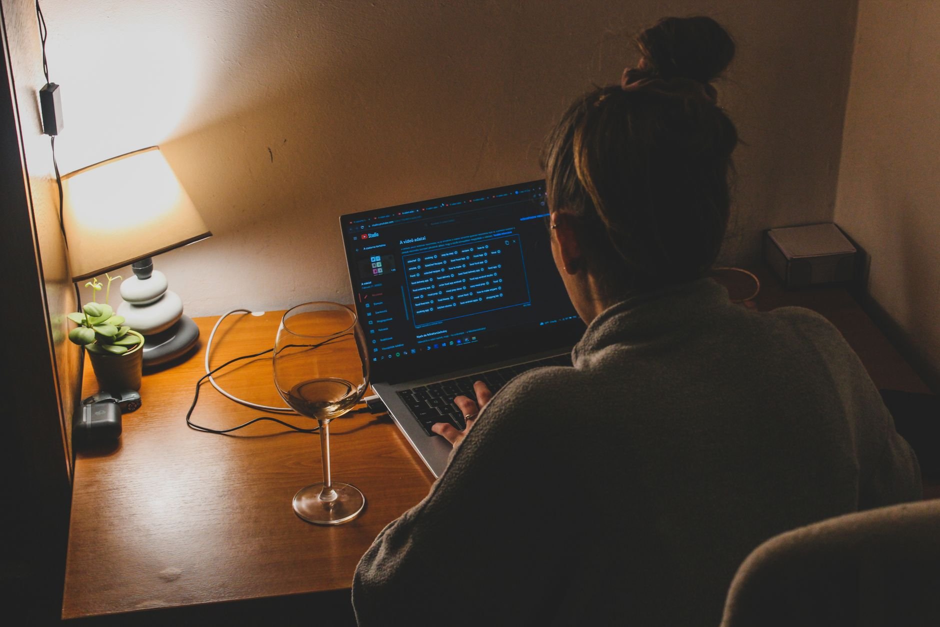 Person working on a laptop late at night with warm lamp lighting